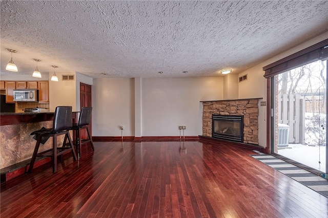 living room featuring visible vents, a fireplace, baseboards, and wood-type flooring