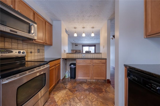 kitchen featuring dark countertops, tasteful backsplash, brown cabinets, appliances with stainless steel finishes, and a textured ceiling