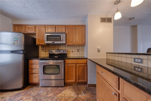 kitchen featuring tasteful backsplash, visible vents, pendant lighting, dark stone counters, and stainless steel appliances