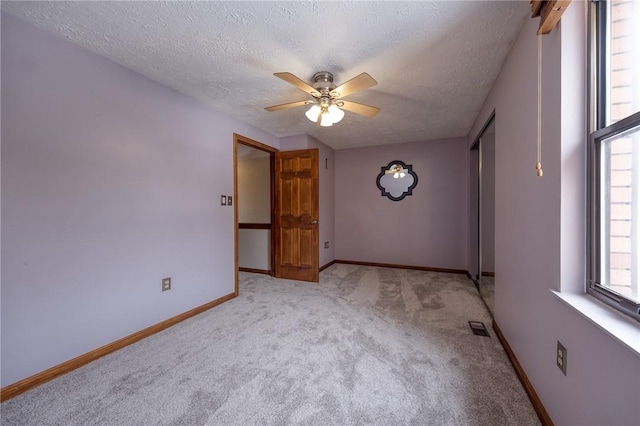 spare room featuring visible vents, ceiling fan, baseboards, light carpet, and a textured ceiling