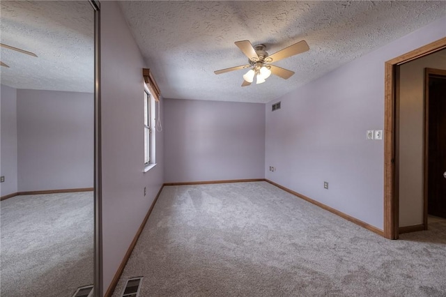 unfurnished bedroom with a textured ceiling, carpet, visible vents, and baseboards