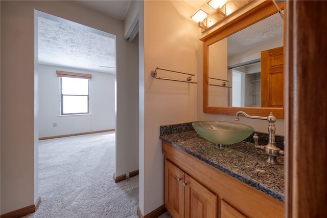 bathroom featuring vanity, baseboards, and a textured ceiling