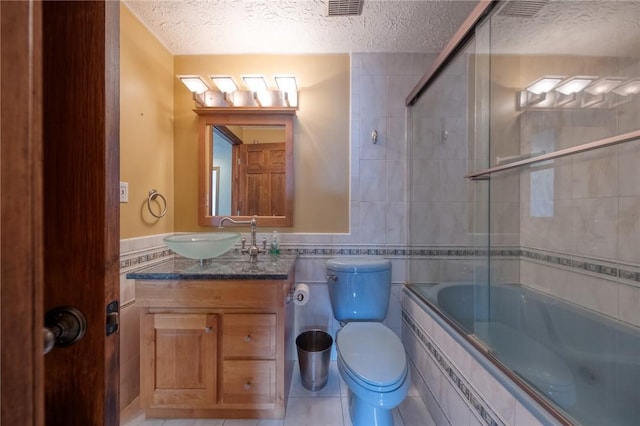 full bathroom with visible vents, tile walls, toilet, tiled shower / bath combo, and a textured ceiling