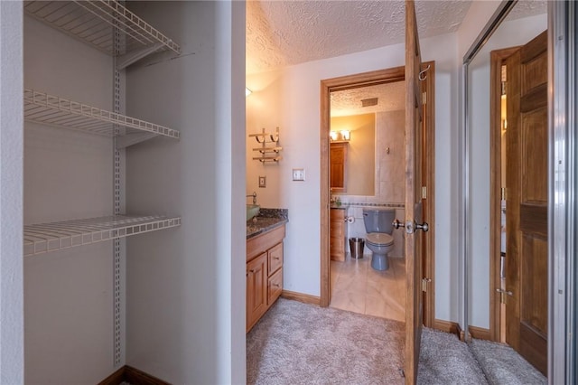 bathroom with toilet, a textured ceiling, vanity, and baseboards