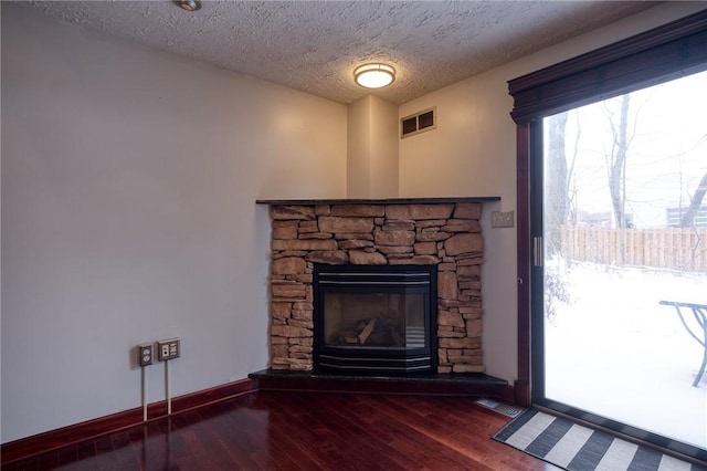 room details with a stone fireplace, wood finished floors, and visible vents