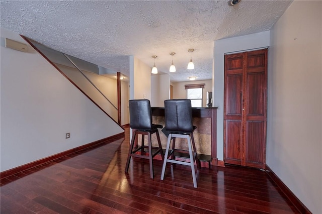 kitchen with hardwood / wood-style floors, a textured ceiling, baseboards, and pendant lighting