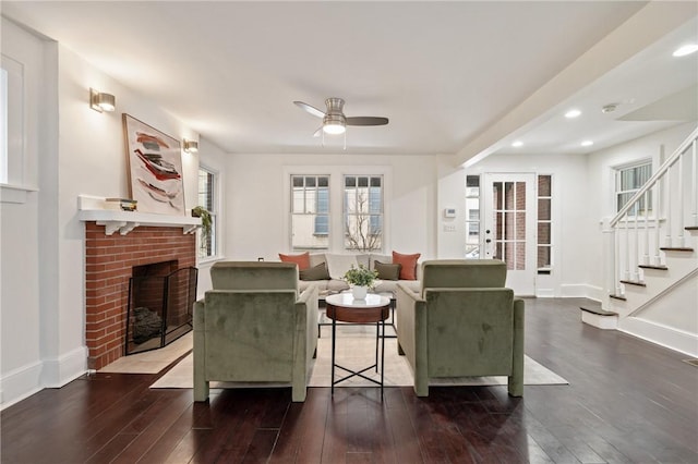 living room featuring stairway, a fireplace, baseboards, and hardwood / wood-style floors