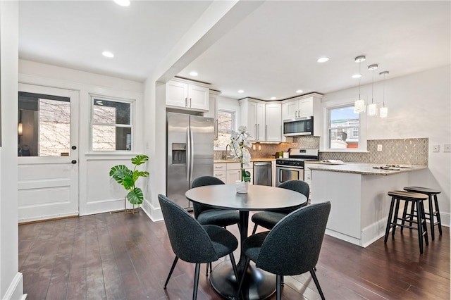 dining room with dark wood-type flooring, recessed lighting, and baseboards