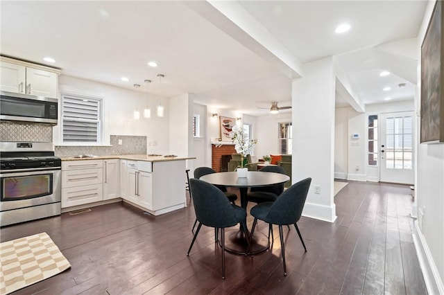 dining room with recessed lighting, a brick fireplace, dark wood-type flooring, and baseboards