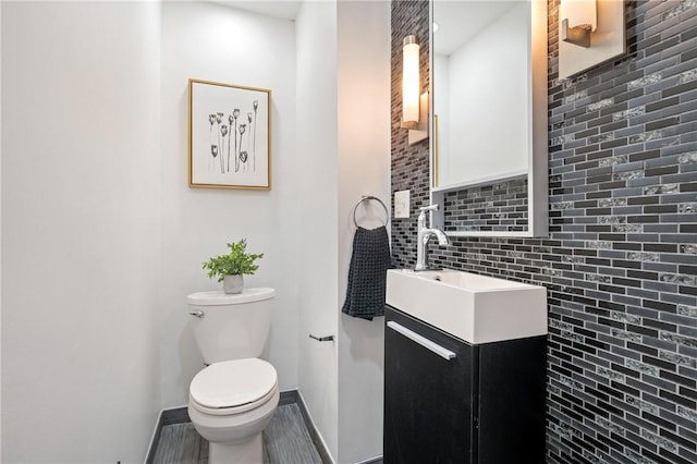 bathroom featuring vanity, decorative backsplash, toilet, and baseboards