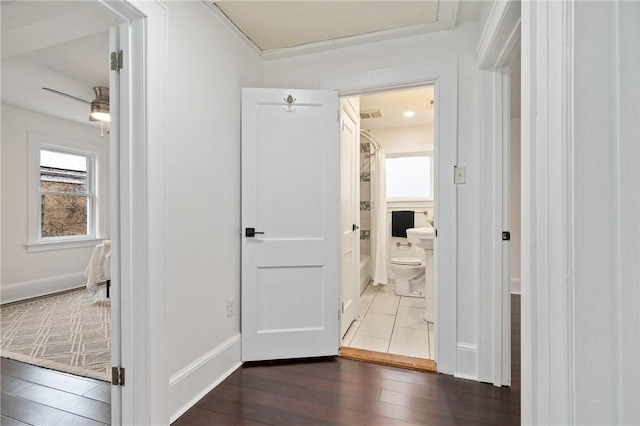 hallway featuring visible vents, baseboards, and wood finished floors