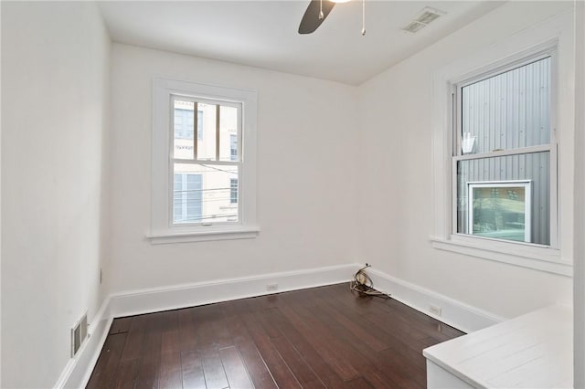 empty room with a ceiling fan, baseboards, visible vents, and dark wood-style flooring