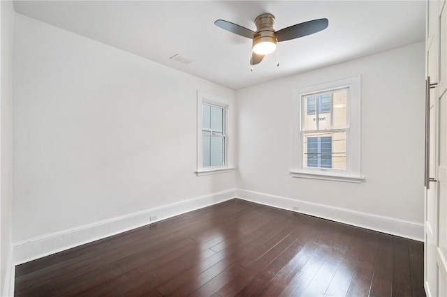 unfurnished room featuring a ceiling fan, baseboards, visible vents, and dark wood-style flooring