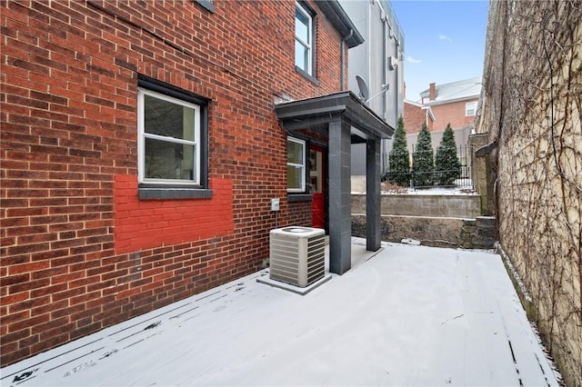 snow covered patio with cooling unit and fence