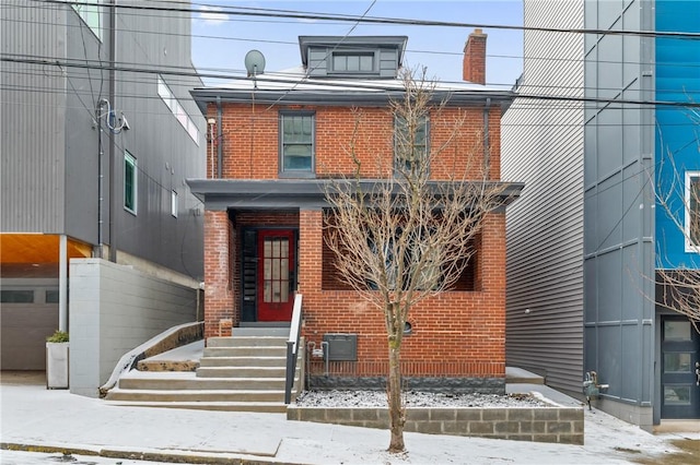 traditional style home with entry steps, brick siding, and a chimney