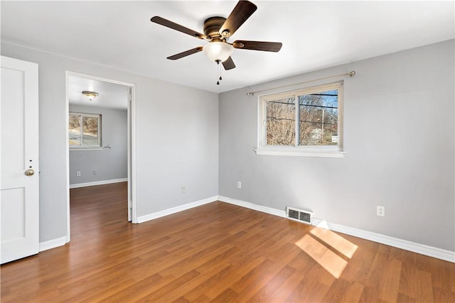 spare room featuring visible vents, wood finished floors, baseboards, and ceiling fan