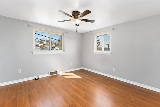 unfurnished room featuring plenty of natural light, wood finished floors, and visible vents