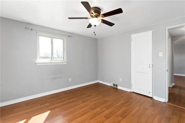 unfurnished room featuring visible vents, a ceiling fan, baseboards, and wood finished floors