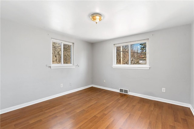 empty room featuring visible vents, baseboards, and wood finished floors