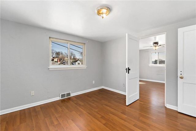 unfurnished room with visible vents, baseboards, and wood finished floors