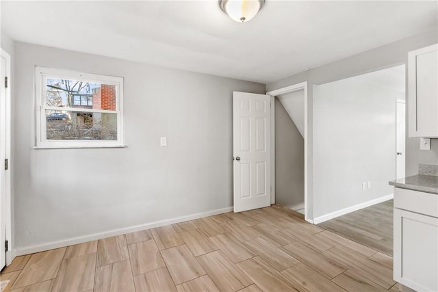 unfurnished room with light wood-type flooring and baseboards