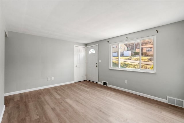 interior space with wood finished floors, baseboards, and visible vents