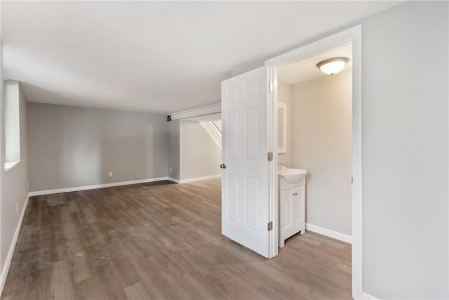 spare room featuring wood finished floors, baseboards, and a sink