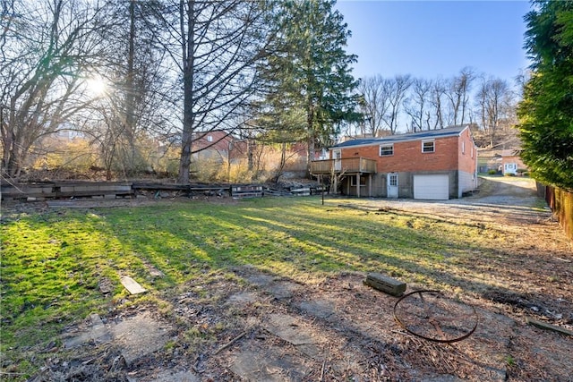 view of yard featuring a wooden deck, an attached garage, and fence