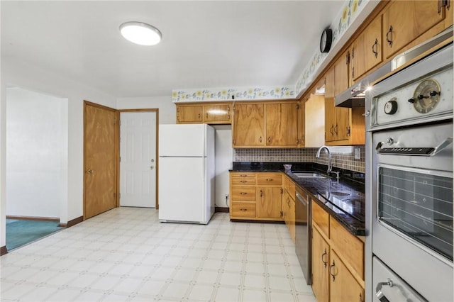 kitchen featuring backsplash, light floors, brown cabinets, white appliances, and a sink