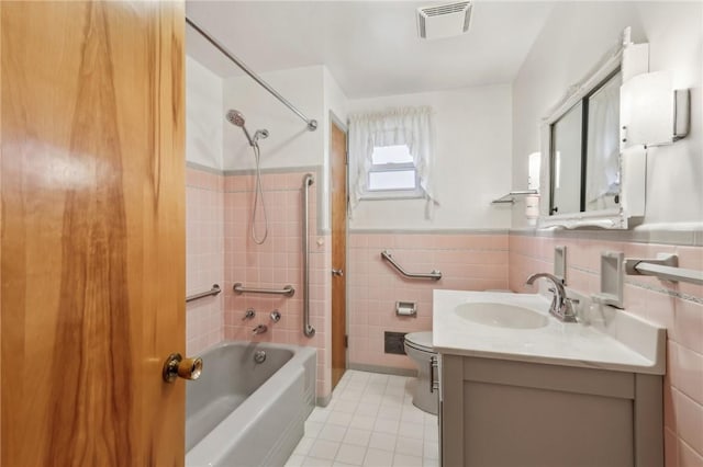 full bathroom featuring visible vents, tile walls, a wainscoted wall, shower / tub combination, and vanity