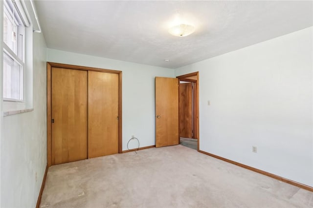 unfurnished bedroom with a closet, baseboards, and light colored carpet