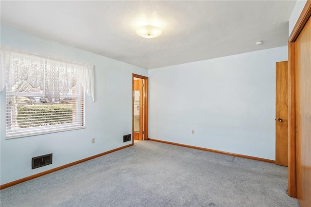 unfurnished room with visible vents, baseboards, and light colored carpet