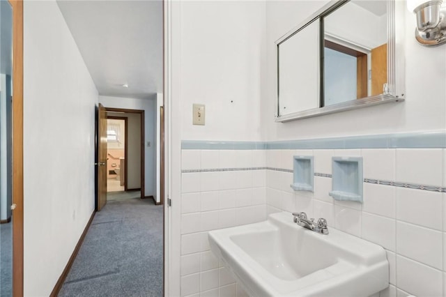 bathroom featuring wainscoting, tile walls, and a sink