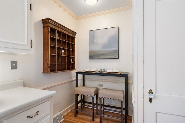 interior space with visible vents, baseboards, wood finished floors, and crown molding