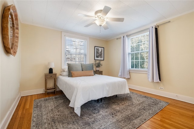 bedroom featuring baseboards, wood finished floors, a ceiling fan, and ornamental molding