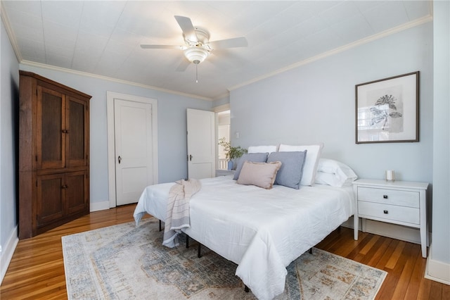 bedroom featuring baseboards, light wood-style floors, ceiling fan, and crown molding