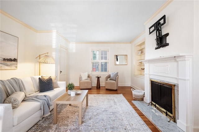 living area featuring a fireplace with flush hearth, built in features, crown molding, baseboards, and dark wood-style flooring