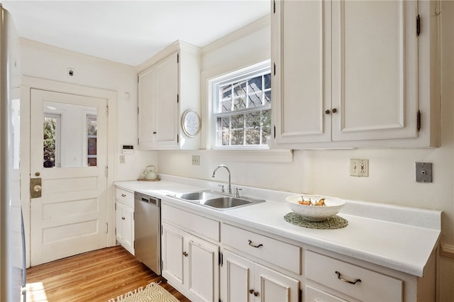 kitchen featuring light wood finished floors, dishwasher, light countertops, white cabinetry, and a sink