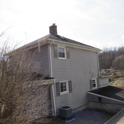 view of home's exterior featuring central AC unit and a chimney