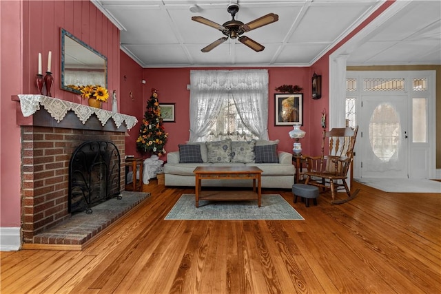 living room featuring a fireplace, crown molding, ceiling fan, and wood finished floors