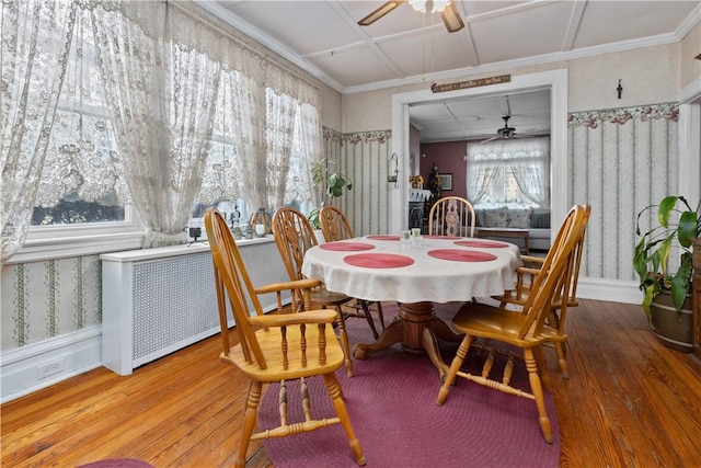 dining space with wood finished floors, a ceiling fan, and wallpapered walls