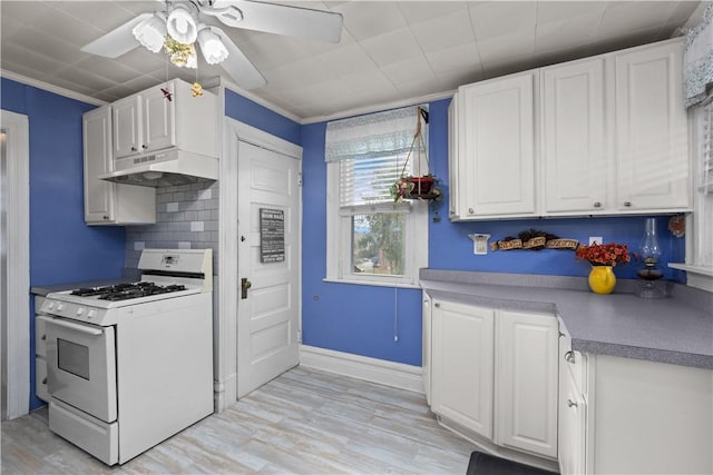 kitchen featuring light wood finished floors, under cabinet range hood, white cabinetry, white gas range, and backsplash