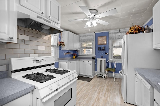 kitchen with white appliances, white cabinets, under cabinet range hood, light wood-type flooring, and backsplash