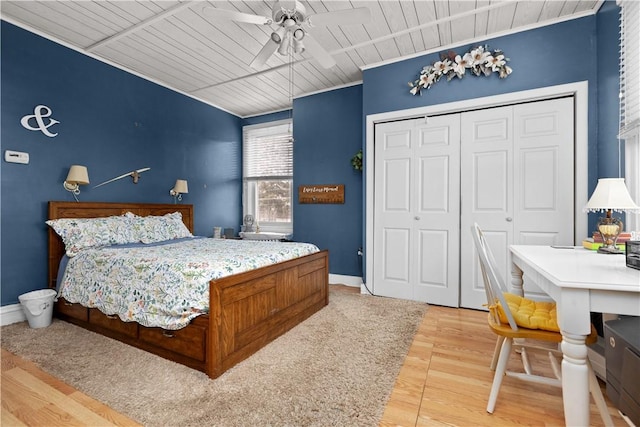 bedroom with a closet, baseboards, wood ceiling, and light wood-style flooring