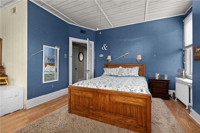 bedroom with visible vents, wood finished floors, radiator, wooden ceiling, and baseboards