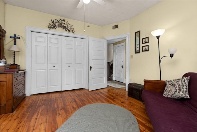 living area with visible vents, a ceiling fan, and hardwood / wood-style flooring