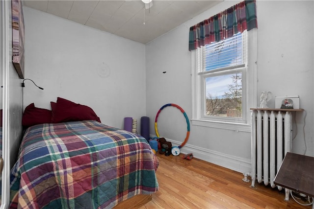 bedroom featuring light wood-style flooring, radiator, and baseboards