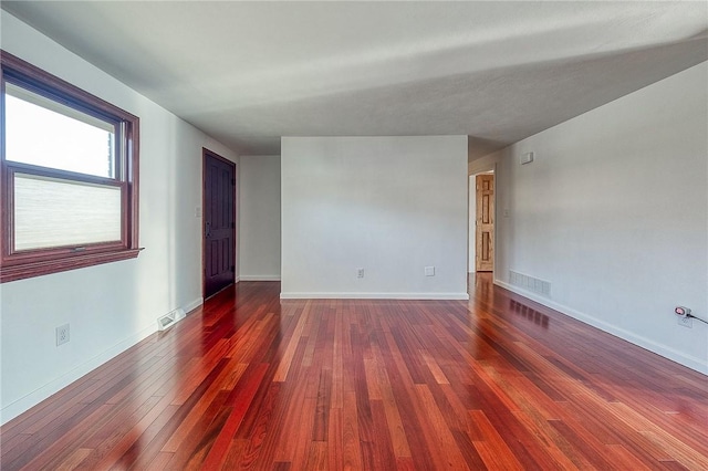 unfurnished room featuring visible vents, baseboards, and hardwood / wood-style floors