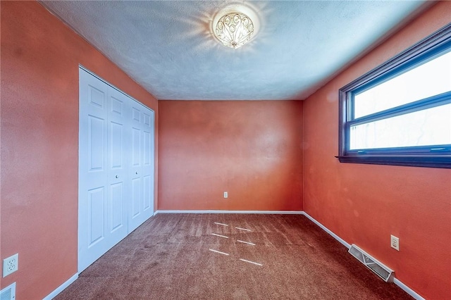 unfurnished bedroom with visible vents, baseboards, carpet flooring, a closet, and a textured ceiling