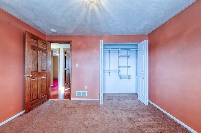 unfurnished bedroom with carpet flooring, baseboards, visible vents, and a closet